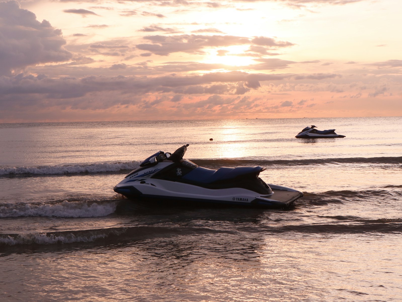 A jet ski in the water with a boat in the background, boat