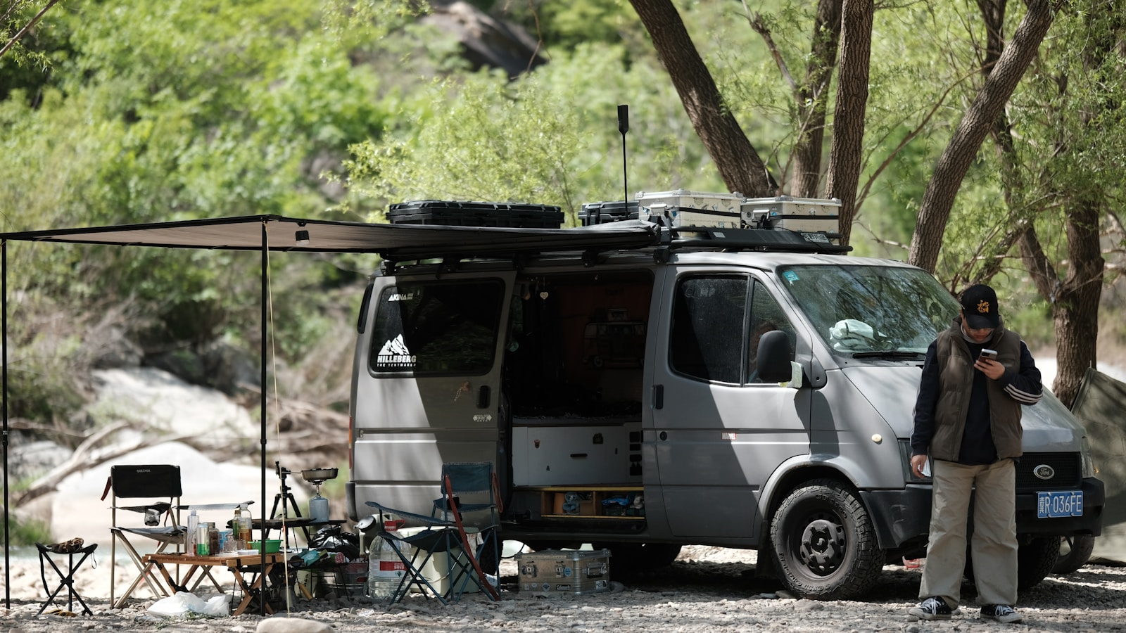 Camper van with awning set up for camping outdoors, RV.